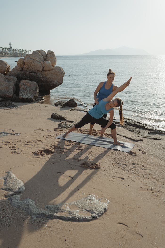 stats-img Two women practicing yoga by the sea, enhancing fitness and relaxation.
