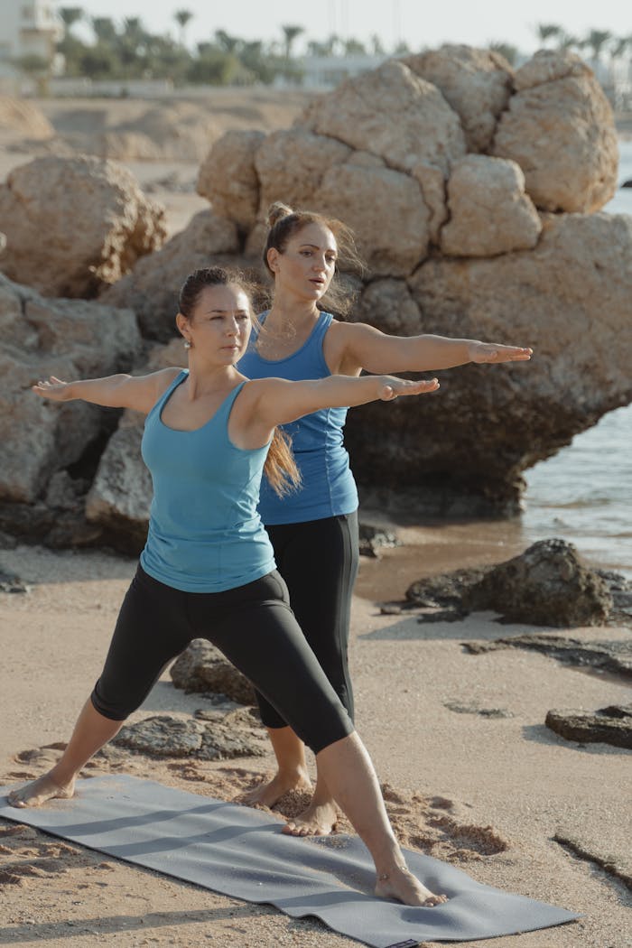 portfolio-03 Two women in yoga poses on a beach showcasing outdoor fitness and mindfulness.
